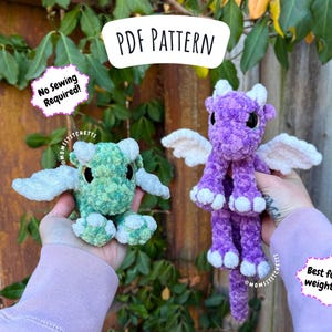 May include: Two plush crochet dragons, one green and one purple, with white wings and horns. The image includes text that says "PDF Pattern" and "No Sewing Required!" and "Best for 5-6 weight yarn".
