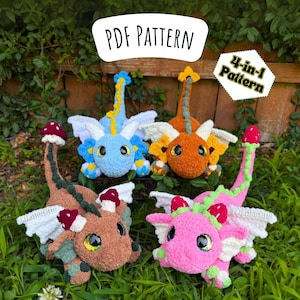 May include: Four crocheted dragon toys in blue, orange, brown, and pink, each with white wings and mushroom accents. The image includes text that reads "Garden Dragon" and "PDF Pattern". A smaller sign says "4-in-1 Pattern".