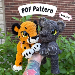 Peut inclure: Deux jouets en peluche faits à la main : un guépard orange avec des taches noires et une panthère grise. Les deux ont de grands yeux brillants. Le guépard a un ventre blanc. L'image comprend le texte "PDF Pattern" et "Low Sew".
