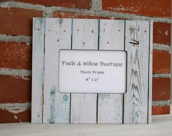 May include: A white wooden photo frame with a distressed finish. The frame has a black mat and says "Finch & Willow Boutique Photo Frame 4" x 6"".