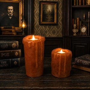 May include: Two cylindrical, amber-colored LED candles with a textured, melted wax appearance. Each candle features a realistic dripping wax effect along the sides and a warm, glowing flame-shaped light at the top, creating a soft illumination.