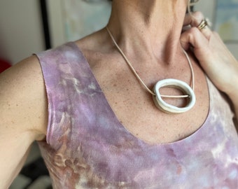 Circle moon statement ceramic necklace on dark clay.