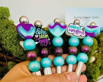 Silicone Beaded makeup brushes with positive, uplifting vibe messages. Bright aqua blue and deep black opal purple beads, lightweight.Hearts