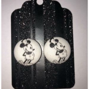 Pode incluir: Um par de brincos de bot&atilde;o branco com uma imagem em preto e branco do Mickey Mouse em cada bot&atilde;o.