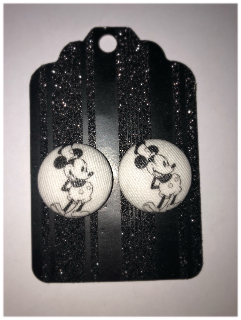 Pode incluir: Um par de brincos de bot&atilde;o branco com uma imagem em preto e branco do Mickey Mouse em cada bot&atilde;o.