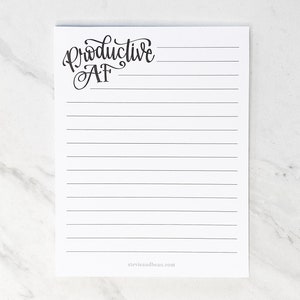 Peut inclure: Un bloc-notes ligné blanc avec le texte "Productive AF" écrit en cursive noire en haut.