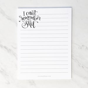 May include: A white notepad with horizontal black lines and the text "I can't remember Shit" in black script. The notepad is blank and ready for notes. The bottom of the notepad has the text "stevieandbean.com".