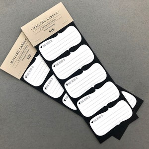 May include: A pack of 18 white mailing labels with a black border and the text "Please deliver to" on each label. The labels are on a black sheet of paper with the text "Mailing Labels" and "518" printed on the top.
