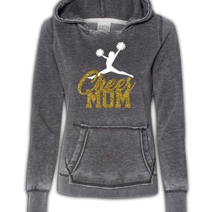 May include: Gray hooded sweatshirt with a white silhouette of a cheerleader and the text "Cheer Mom" in gold glitter.