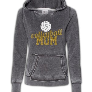 May include: Gray hooded sweatshirt with a distressed look. The sweatshirt has a white volleyball graphic and gold glitter text that reads "volleyball MOM".