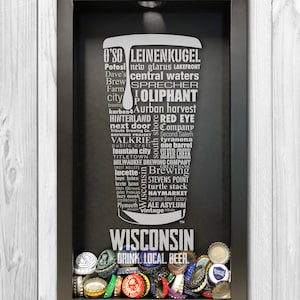 May include: A black framed shadow box with a white silhouette of a beer bottle and the words "Wisconsin Drink Local Beer" printed on the bottom. The box is filled with a variety of colorful bottle caps.