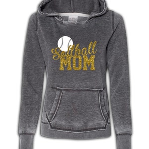 May include: A gray hooded sweatshirt with a distressed look. The sweatshirt has a large gold glitter graphic that says "Softball Mom" with a white softball graphic above the text.