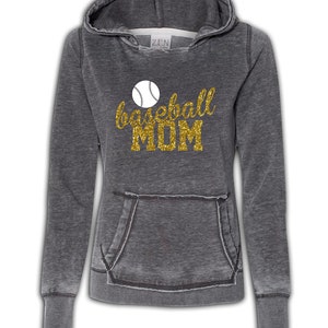 May include: A gray hooded sweatshirt with a distressed look. The front of the sweatshirt has a gold glitter design that says "baseball MOM" with a white baseball graphic.