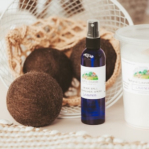 May include: A set of natural laundry products including a bottle of lavender dryer ball refresher spray, a container of lavender laundry soap, and three brown wool dryer balls.