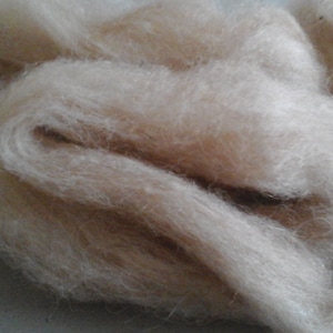 Op de afbeelding: Een close-up van een stapel lichtbruine, pluche alpaca-vezels.