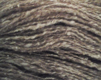 Puede incluir: Primer plano de una madeja de hilo de color marrón y blanco. El hilo está hecho de fibras naturales y tiene una textura suave y peluda.