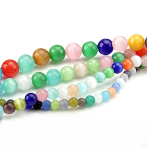 May include: Close-up of several strands of colorful round beads in various sizes. The beads are in shades of red, blue, green, pink, yellow, and white. The beads are strung together, creating a vibrant and eye-catching display.
