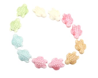 May include: A selection of small ceramic turtle figurines in pastel shades of green, blue, pink, and beige. The turtles are arranged in a circle against a white backdrop.