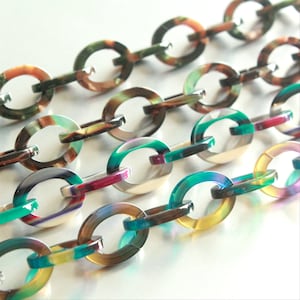 May include: A chain made of oval-shaped links with a multi-colored swirl pattern. The links are translucent and have a glossy finish. The chain is made of plastic.