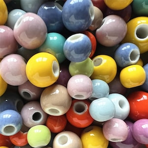 May include: A collection of colourful ceramic beads with a hole in the centre. The beads are various shades of blue, green, yellow, pink, orange, and brown.