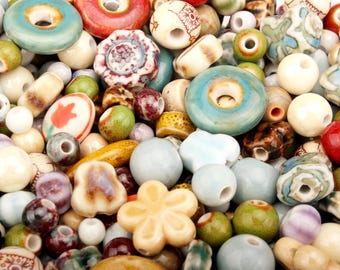 May include: A collection of colorful beads in various shapes and sizes. The beads include round, oval, and flower-shaped designs, with colors like turquoise, red, cream, and green. Some beads have patterns, and all have holes for stringing.