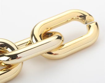 May include: Close-up of a gold chain link. The chain is made of thick, oval-shaped links.