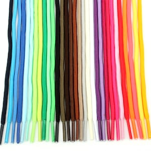 May include: A collection of colorful shoelaces in various shades, including black, blue, green, brown, pink, red, orange, and yellow. The shoelaces are arranged vertically, showcasing their vibrant hues and contrasting tips.