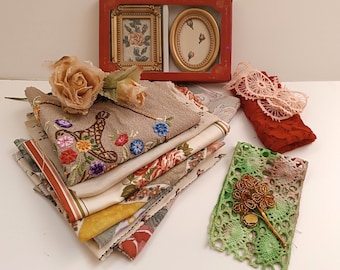 Könnte beinhalten: Eine Sammlung von Artikeln im Vintage-Stil, darunter bestickter Stoff, florale Taschentücher und eine rote Schachtel mit zwei kleinen Bilderrahmen. Eine beige Rose und ein grüner Spitzenartikel mit einer goldenen Brosche sind ebenfalls vorhanden.