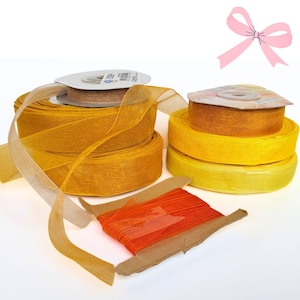 Peut inclure: Divers rubans décoratifs dans des tons de jaune, orange et marron. Les rubans sont sur des bobines et des rouleaux, avec un motif de nœud rose clair dans le coin supérieur droit. Idéal pour l'artisanat, l'emballage de cadeaux et d'autres projets créatifs.