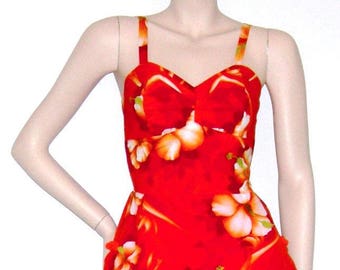 May include: A red and white floral print swimsuit with a sweetheart neckline and thin straps. The swimsuit has a full skirt and is made of a lightweight fabric.