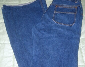 Può includere: Un paio di jeans blu denim a gamba larga con una sola tasca posteriore. I jeans hanno un orlo sfrangiato.