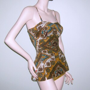 May include: A vintage-style swimsuit with a brown, gold, and blue geometric pattern. The swimsuit has a halter top and a skirt-like bottom.