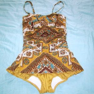 May include: A vintage yellow and brown patterned swimsuit with a halter top and a ruffled skirt.