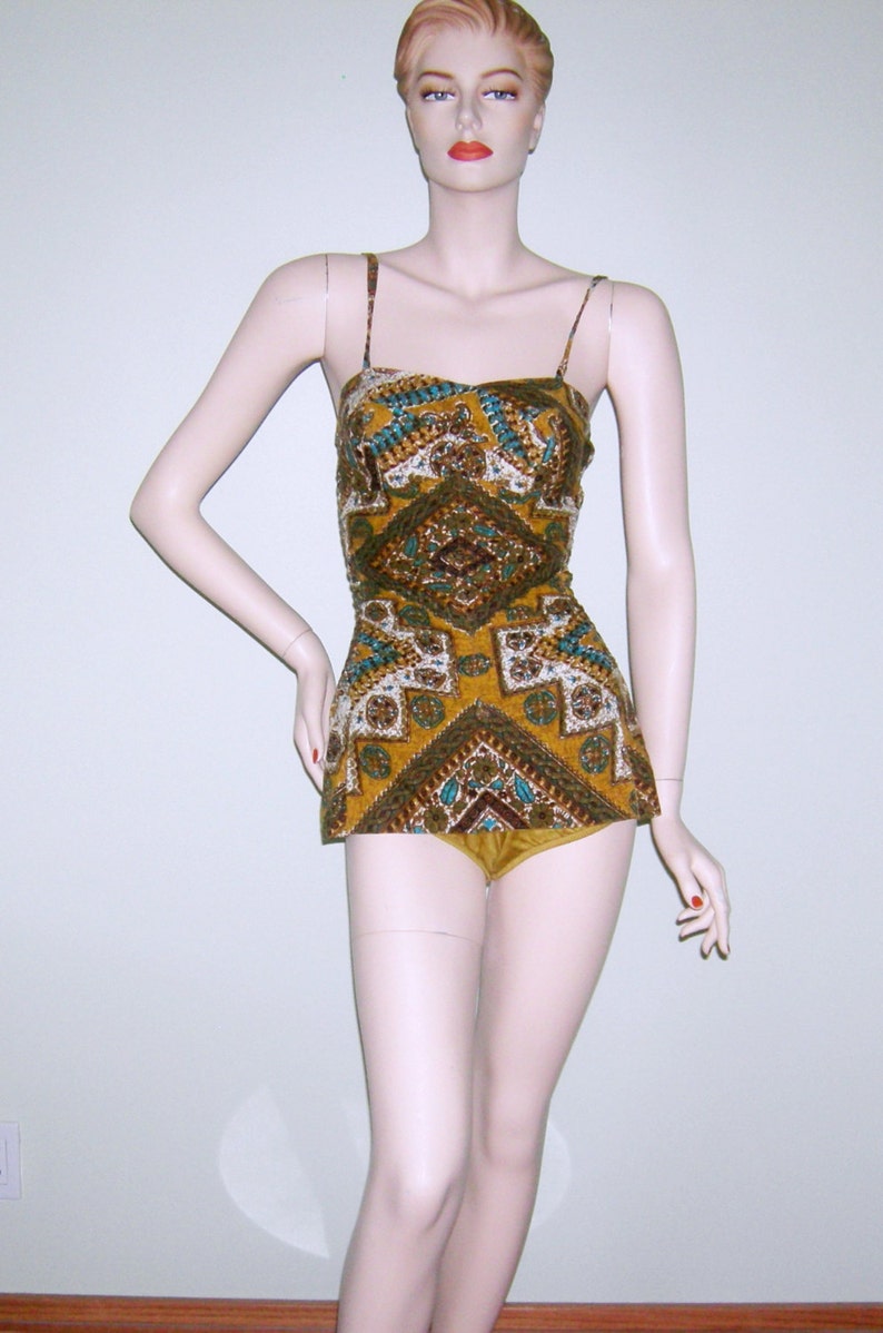 May include: A vintage swimsuit with a geometric pattern in shades of brown, gold, and turquoise. The swimsuit has a halter top and a high-waisted bottom.