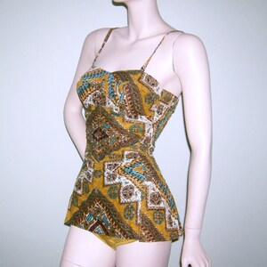 May include: A vintage swimsuit with a geometric pattern in shades of brown, yellow, blue, and white. The swimsuit has a fitted bodice and a full skirt.