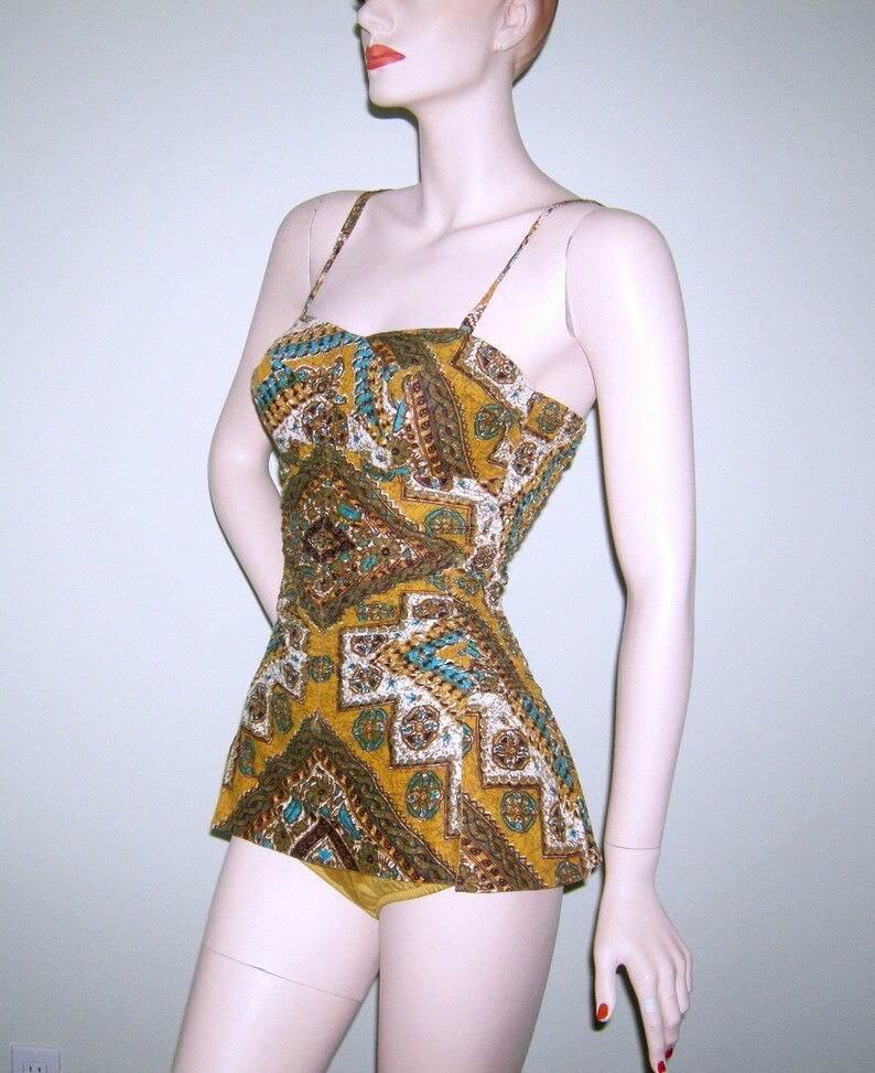 May include: A vintage swimsuit with a geometric pattern in shades of brown, yellow, blue, and white. The swimsuit has a fitted bodice and a full skirt.