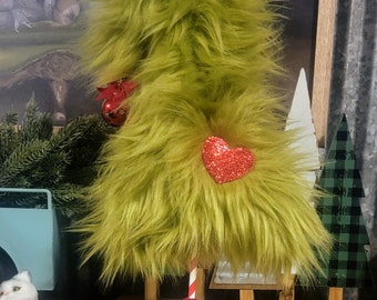 May include: A green fuzzy Christmas tree with a red glitter heart and a red ornament. The tree is on a red and white striped stick and a red glitter base.