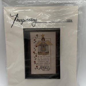 May include: Cross stitch pattern featuring a whimsical angel with a star above its head. The pattern includes the text "We are not alone. We are assisted and defended by a powerful and glorious order of invisible beings. Angels."