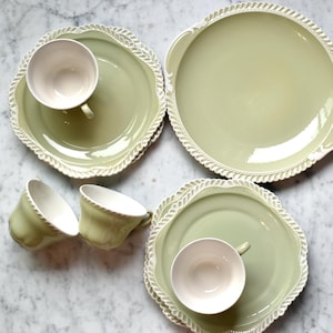 May include: A set of green and white ceramic teacups and saucers with a decorative edge. The set includes a larger serving plate with handles.
