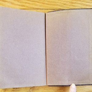 May include: A brown leather-bound book with a blank cover. The book is open to reveal blank pages.