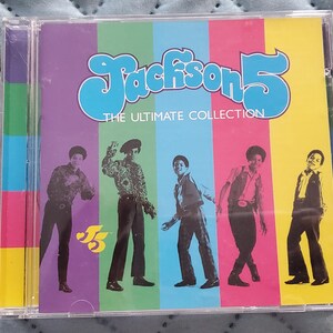 May include: A Jackson 5 The Ultimate Collection music CD in a clear plastic jewel case. The cover features five black and white silhouettes of the band members against vertical stripes of purple, green, blue, pink, and yellow, with blue text.