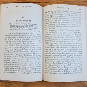 May include: An open book with yellowed pages, showing an excerpt from the essay "The Over-Soul" by Ralph Waldo Emerson. The text discusses the concept of a higher power and the interconnectedness of all things.