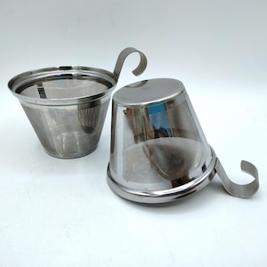 May include: Two silver-colored stainless steel tea infusers with a conical mesh body and a curved handle. One infuser is positioned upright, while the other is placed on its side, showcasing the fine metal mesh construction and polished rim.
