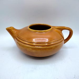 May include: A white ceramic mug with a black handle and the text "But First, Coffee" in a black, bold font. The mug is on a white surface.