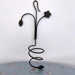 May include: Black metal wine bottle holder with a spiral design and decorative leaf accents.