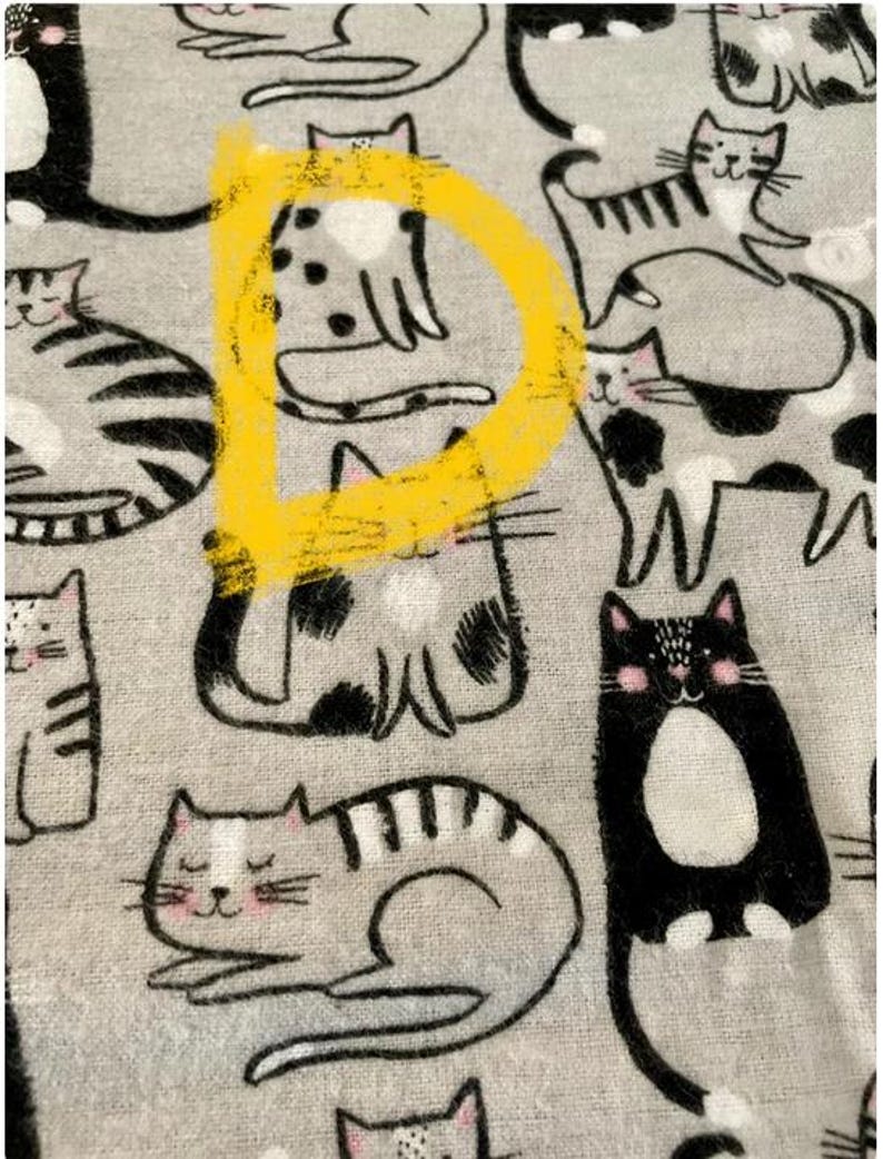 May include: A gray fabric with a repeating pattern of black and white cats. The cats are in various poses, including sitting, lying down, and standing. One cat is highlighted with a yellow circle.