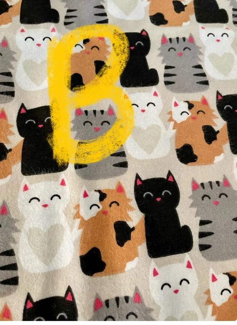 May include: A beige fabric with a repeating pattern of black, white, gray, and brown cats. The cats are all smiling and have different patterns on their fur. The fabric is perfect for crafting projects, such as making pillows, blankets, or tote bags.
