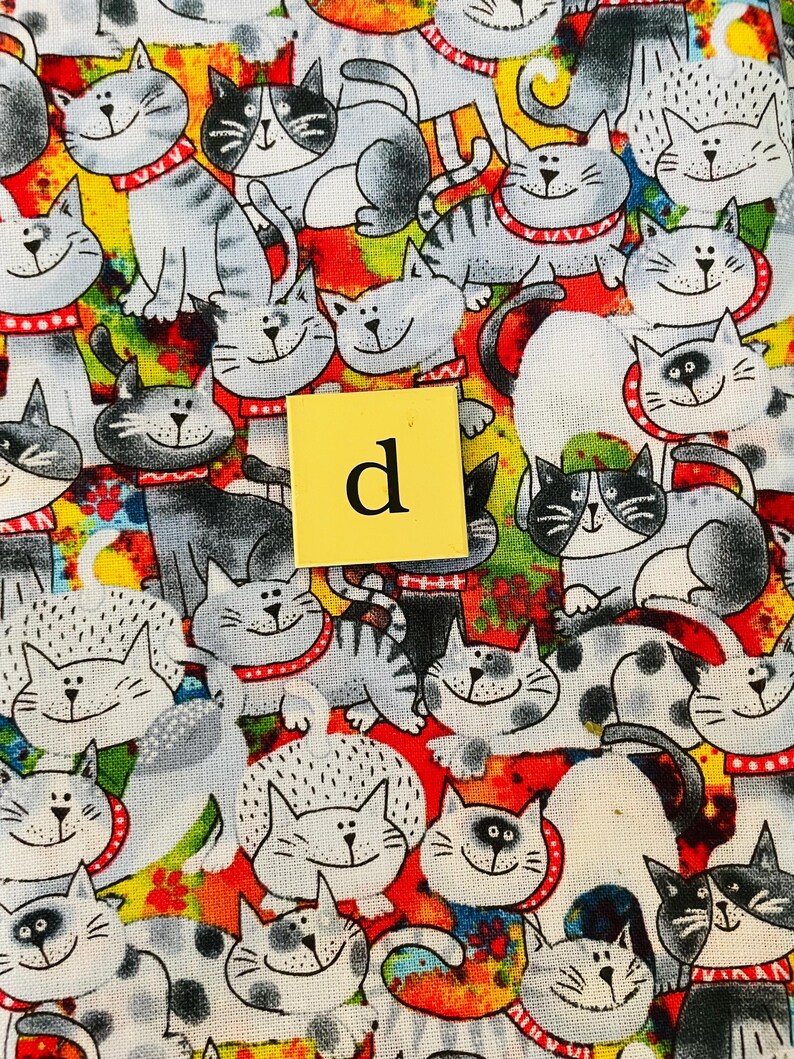 Pode incluir: Um tecido colorido com um padr&atilde;o repetitivo de gatos de desenho animado. Os gatos s&atilde;o desenhados em preto e branco com colares vermelhos e s&atilde;o colocados sobre um fundo de cores brilhantes, incluindo vermelho, amarelo, laranja, verde e azul.