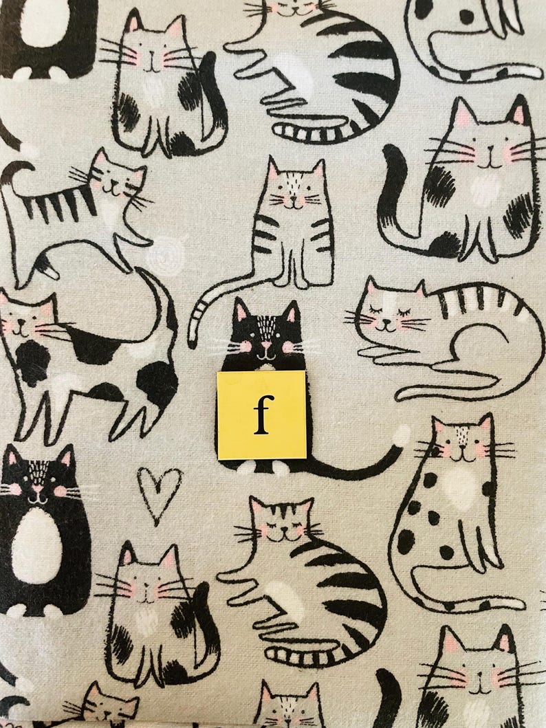 Pode incluir: Um tecido cinza e branco com um padr&atilde;o repetido de gatos pretos e brancos. Os gatos est&atilde;o em v&aacute;rias poses, incluindo sentados, deitados e em p&eacute;. O tecido tem uma textura sutil e um fundo cinza claro.