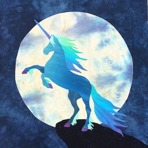 Puede incluir: Un unicornio azul con un cuerno plateado se encuentra de pie sobre una roca con el fondo de una gran luna blanca con nubes azules. La crin y la cola del unicornio son un degradado de azul y verde.
